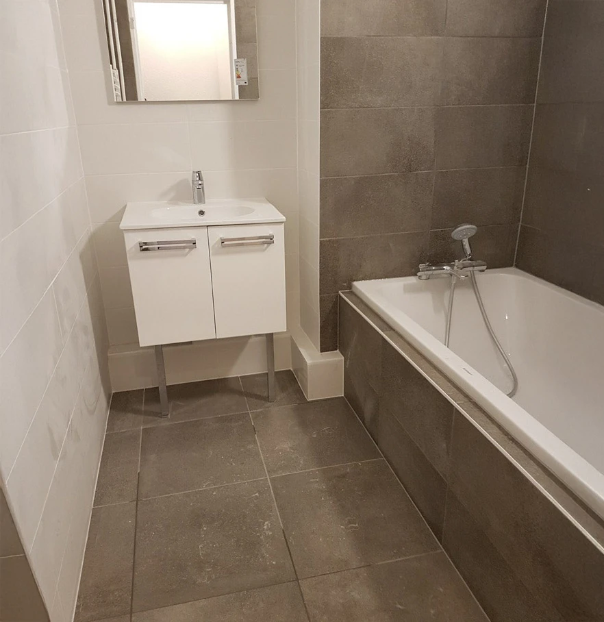 Salle de bains moderne rénovée avec baignoire encastrée et meuble vasque suspendu blanc