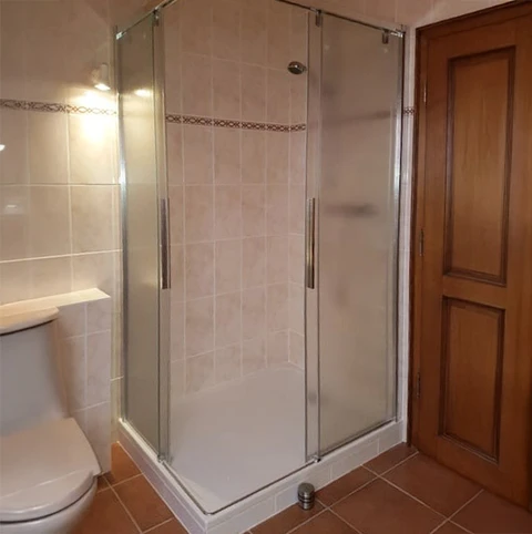 Salle de bain moderne avec douche d'angle à portes coulissantes en verre trempé, cadre chromé