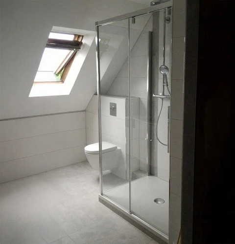 Salle de bain mansardée moderne avec douche à l'italienne et toilettes suspendues