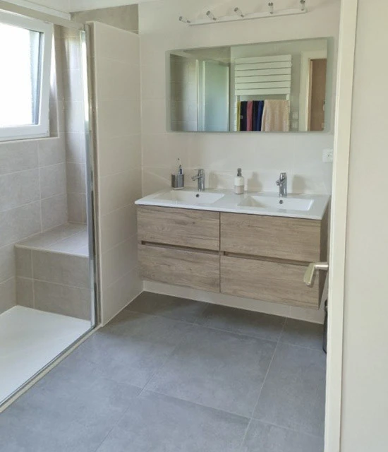 Salle de bain moderne avec douche à l'italienne équipée d'une colonne de douche thermostatique chromée, pommeau de tête rond et douchette à main