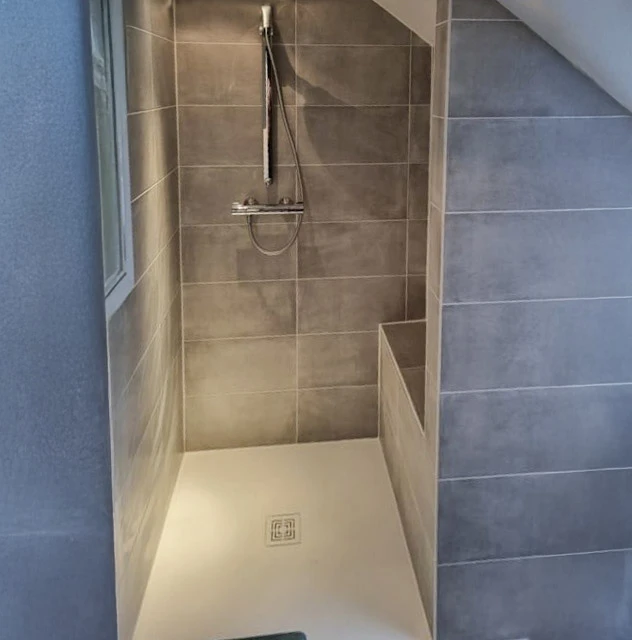 Salle de bain moderne avec baignoire d'angle équipée d'un pare-douche en verre, WC suspendu blanc, meuble vasque suspendu blanc avec plan de toilette intégré et robinetterie chromée