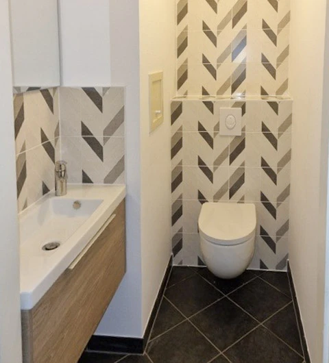 Salle de bain moderne avec douche à l'italienne vitrée, meuble vasque suspendu en bois naturel avec plan blanc intégré, colonne de rangement assortie et miroir éclairé