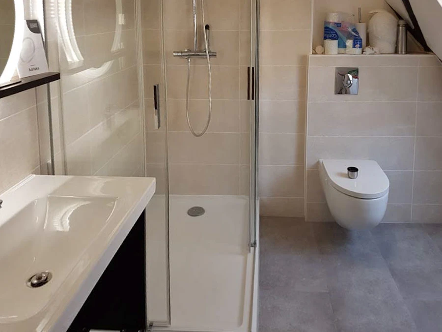 Salle de bain moderne avec douche italienne à paroi vitrée, receveur blanc et carrelage mural gris