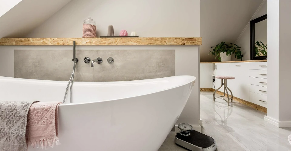 Plombier professionnel en combinaison bleue et gants noirs travaillant dans salle de bain carrelée blanche
