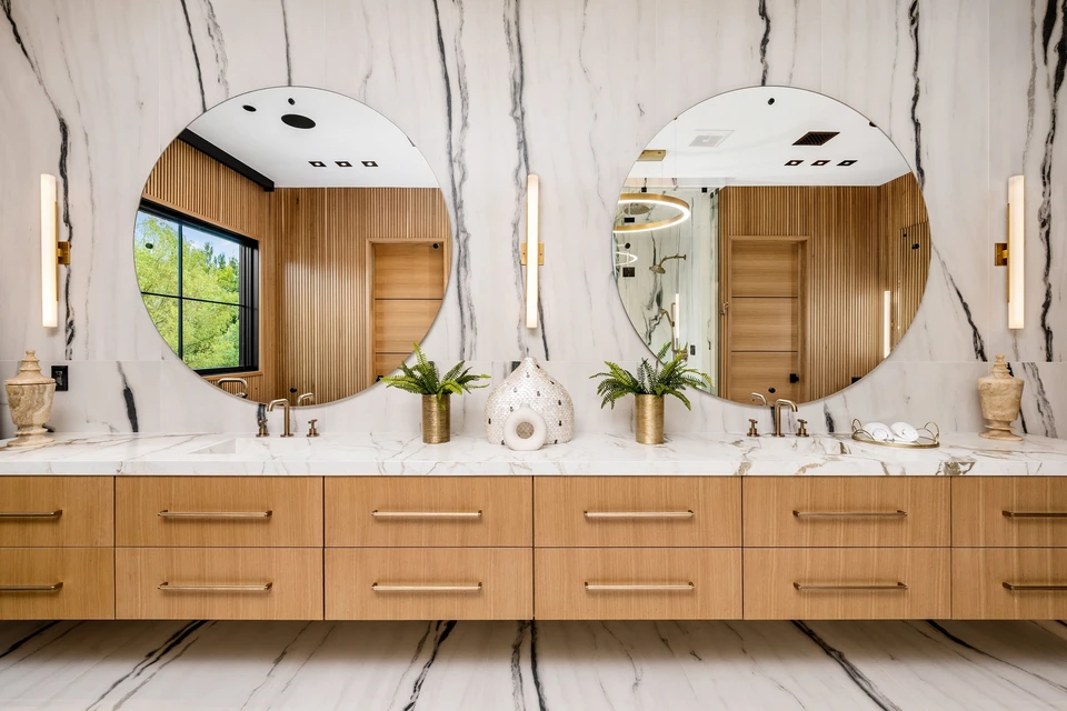 Salle de bain moderne haut de gamme avec baignoire îlot blanche ovale, douche à l'italienne avec paroi vitrée, double vasque sur meuble suspendu anthracite