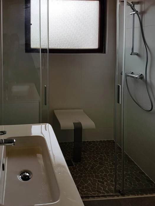 Salle de bain moderne rénovée avec douche à l'italienne, parois vitrées transparentes, vasque suspendue blanche, baignoire encastrée et fenêtre naturelle