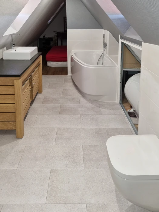 Salle de bain moderne sous combles avec baignoire d'angle blanche et cabine de douche vitrée