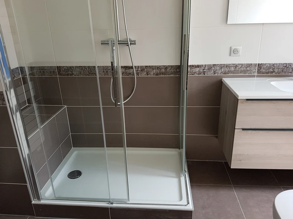 Salle de bain moderne avec douche d'angle à portes coulissantes en verre trempé transparent