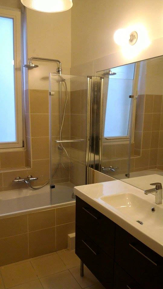 Salle de bain moderne sous combles avec baignoire d'angle blanche et cabine de douche vitrée