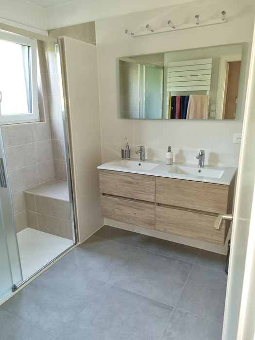 Salle de bain moderne avec douche à l'italienne équipée d'une colonne de douche thermostatique chromée, pommeau de tête rond et douchette à main