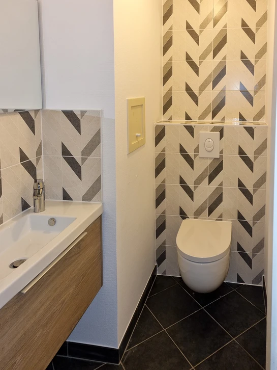 Plombier professionnel en salopette bleue et chemise à carreaux travaille dans une salle de bain moderne