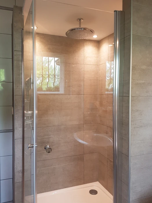 Salle de bain moderne avec douche à l'italienne vitrée, WC suspendu blanc et sèche-serviettes vertical blanc
