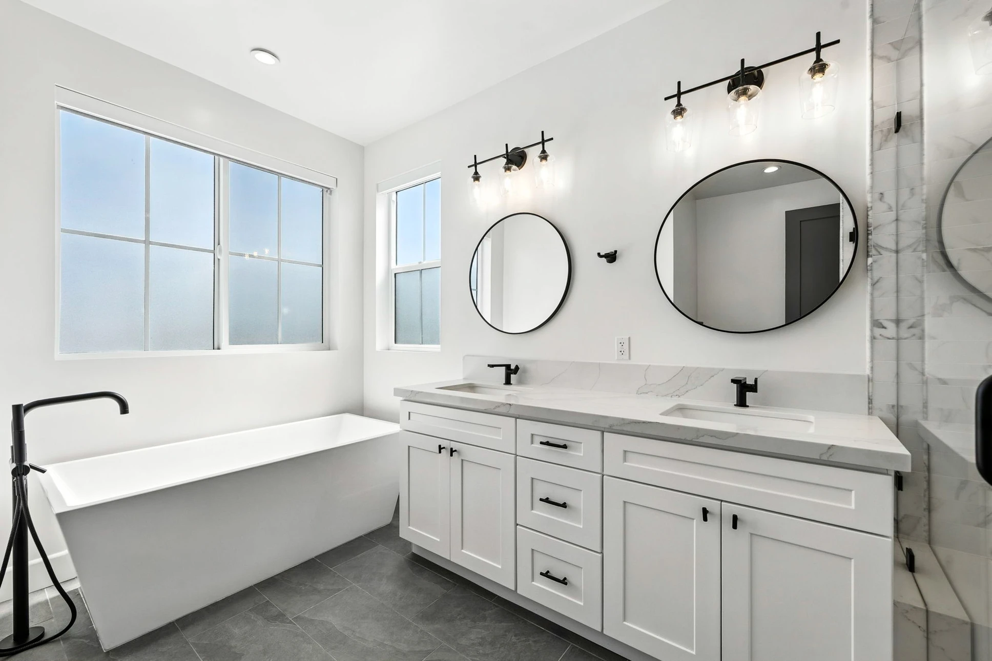 Salle de bains moderne avec baignoire blanche, lavabo rond sur meuble suspendu noir, robinetterie murale
